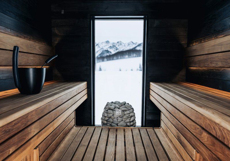A wooden sauna room with a window and stacked sauna stones